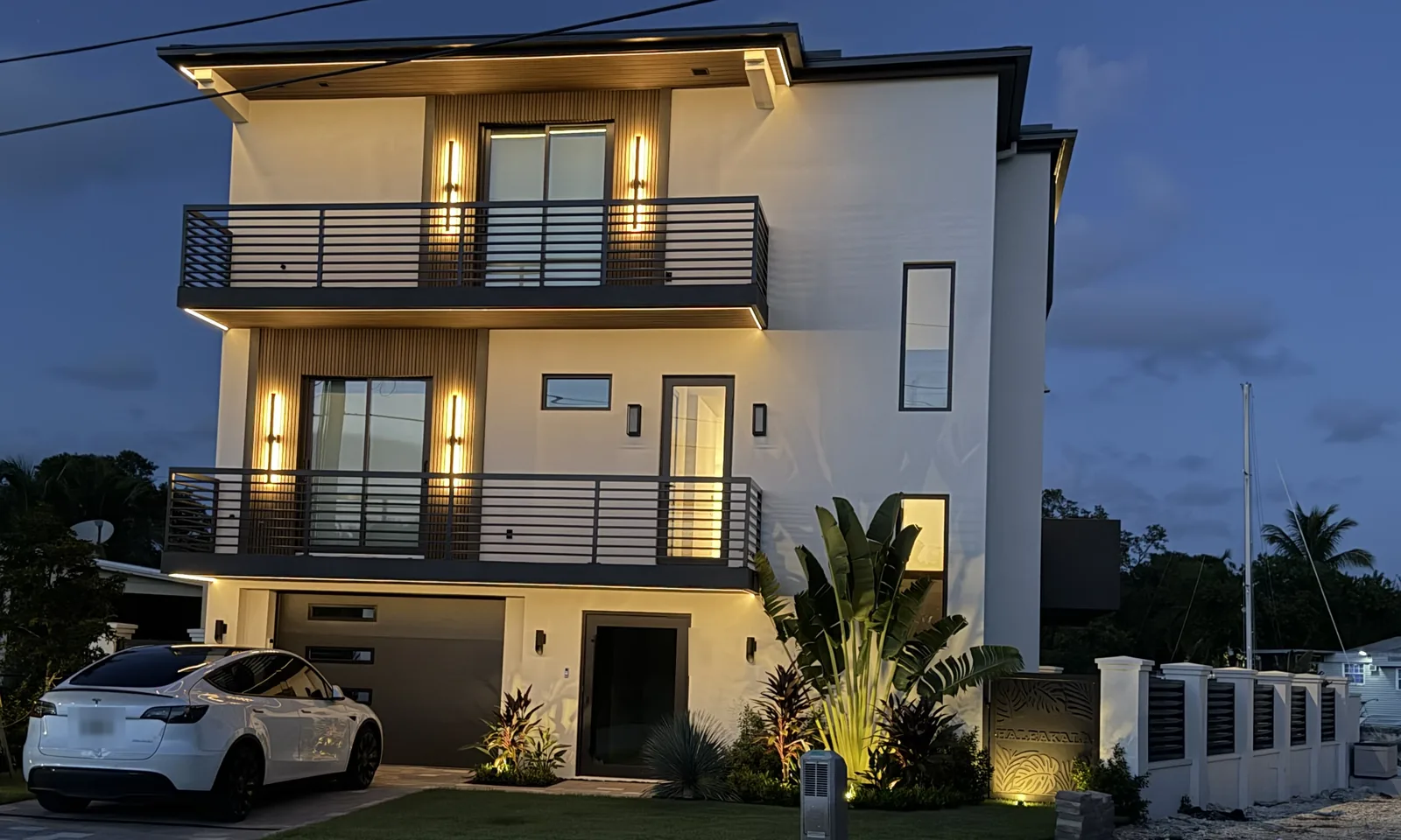 Modern three-story home at dusk with exterior LED lighting by PTM Electric